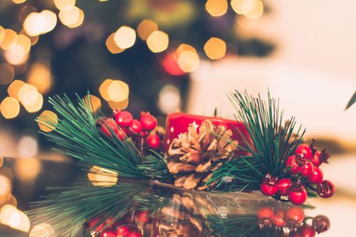 Free A vibrant Christmas scene with a red candle, pine cone, and berries, surrounded by holiday bokeh lights. Stock Photo