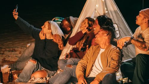 Free A diverse group of friends enjoying a lively beach night party, capturing memories with a selfie. Stock Photo