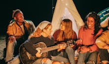 Group of Friends Singing while Sitting on Beach Sand