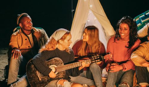Free A group of friends enjoying music and togetherness by a beach bonfire at night. Stock Photo