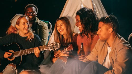 Free Group of Friends Singing while Sitting on Beach Sand Stock Photo
