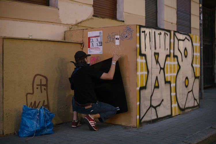 Person Posting Black Textile On Container Wall