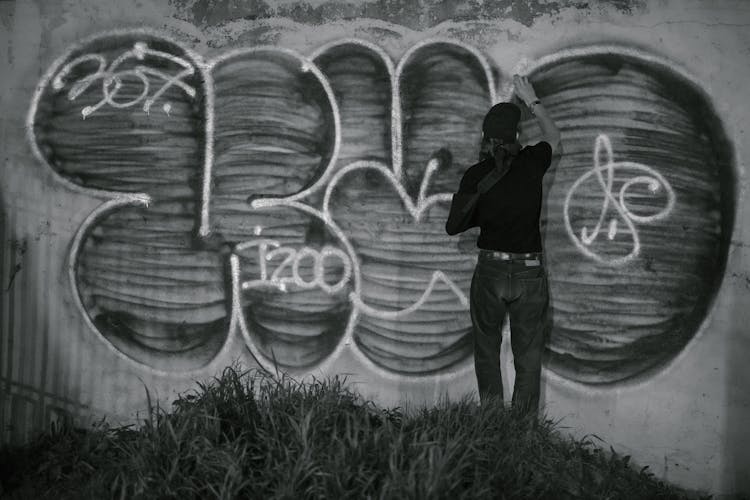 Person Creating Graffiti Art On Wall