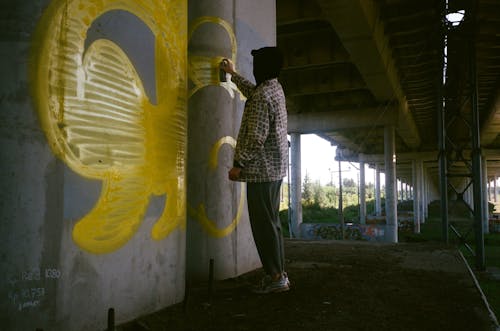 Graffitist Spray Painting a Concrete Column