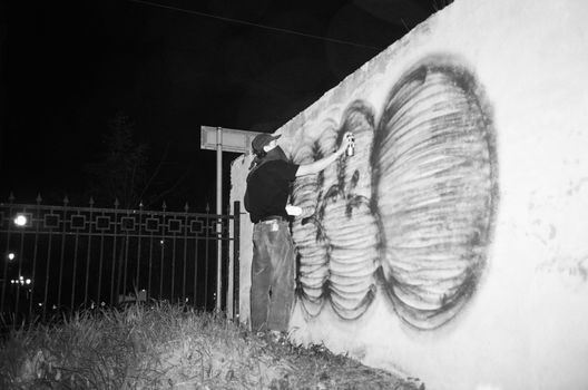 Man Spray Painting a Concrete Fence