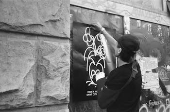 Man with a Broken Arm Hanging a Poster on a Wall in City 