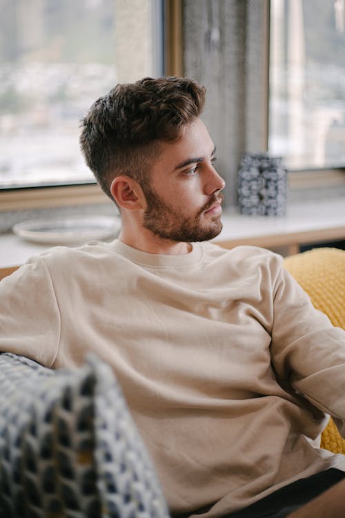 A Bearded Man Wearing Sweater while Sitting on the Couch