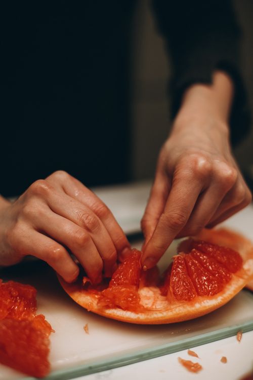 Free Hands carefully holding grapefruit pieces, emphasizing texture and freshness. Stock Photo