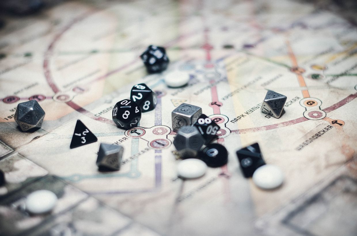 Polyhedral dice scattered across a hand-drawn map — photo by Nika Benedictova on Pexels