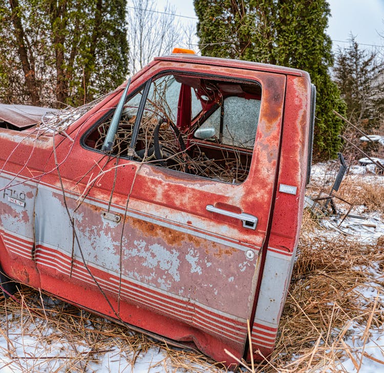 Junk Car Front Of Red Pick Up Truck On Brown Grass 