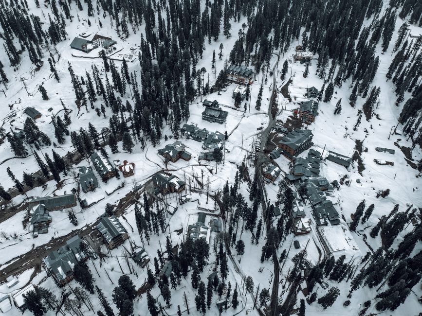 Best Time To See Snow In Kashmir 2 Snow-covered aerial view of Gulmarg, showcasing buildings and pine trees in winter.