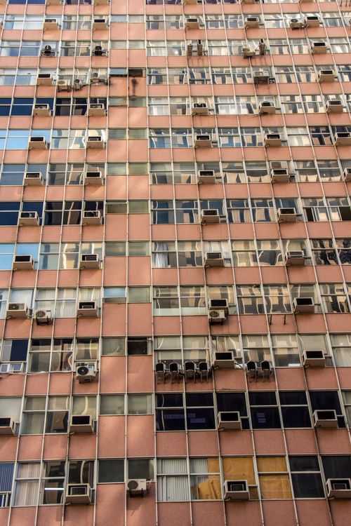 Free Vertical shot of a building facade covered with windows and air conditioning units. Stock Photo
