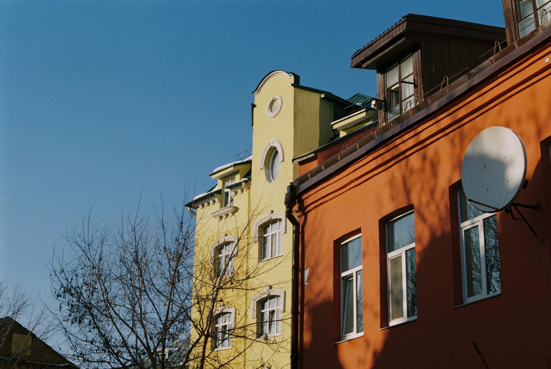Vibrant yellow and orange buildings in Minsk against a clear blue sky, showcasing urban architecture.