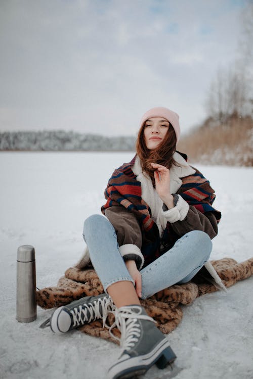 Woman Sitting on a Blanket Place on Ground Covered with Snow
