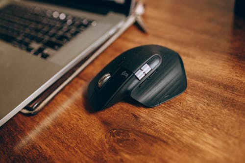 Black Cordless Computer Mouse on Brown Wooden Desk