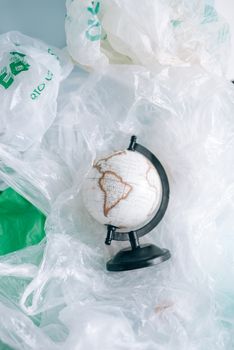 A globe resting in a pile of crumpled plastic bags symbolizes environmental pollution. — photo by Leeloo The First