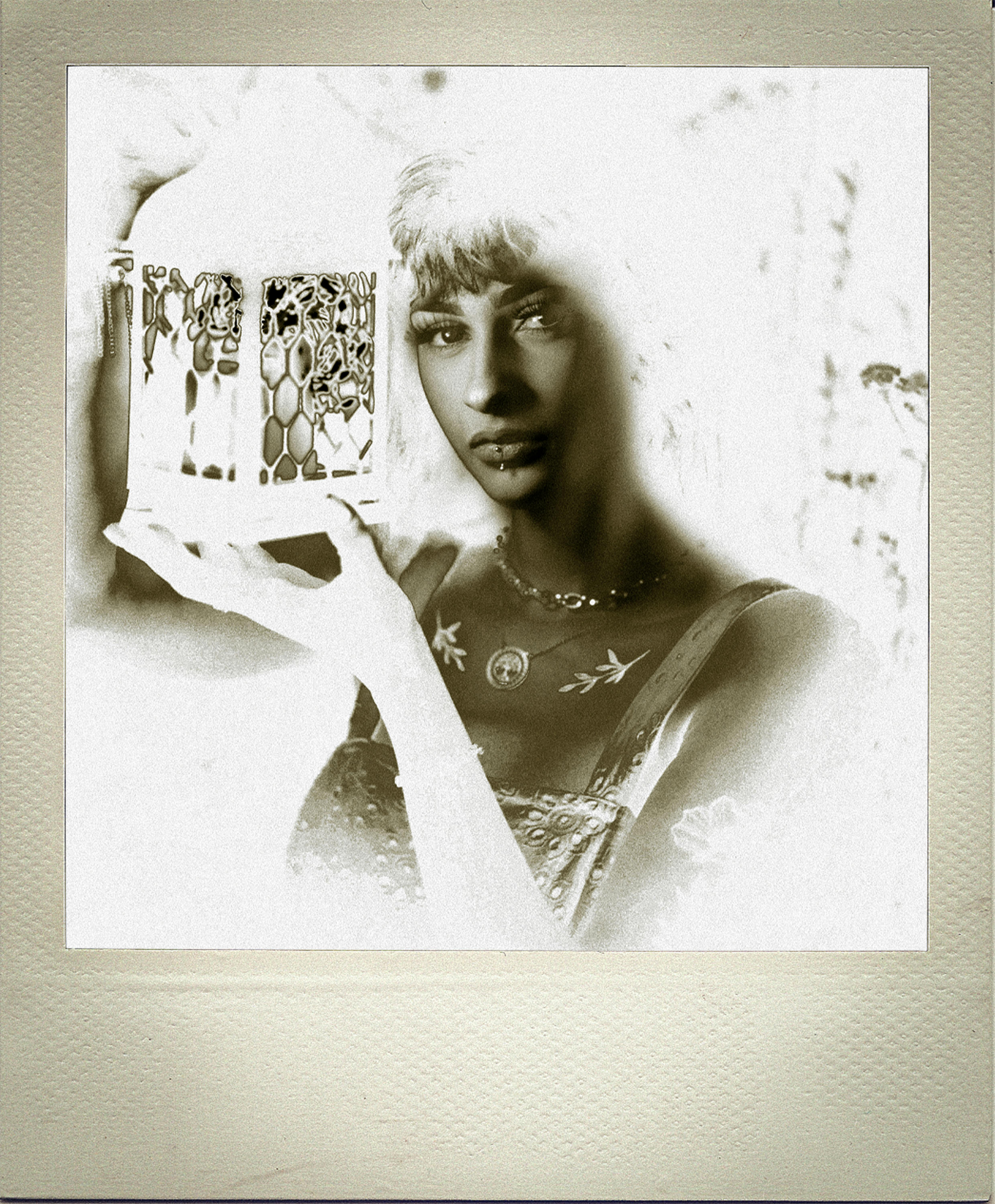 Negative image of calm female with creative tattoo and chain with old fashioned metal lantern in hands looking at camera