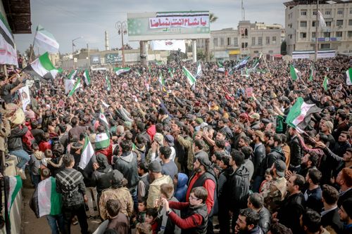 Free Thousands gather in Idlib, Syria, holding flags and signs in a large-scale protest against the government. Stock Photo
