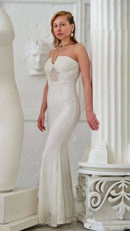 Woman in elegant dress near white sculptures