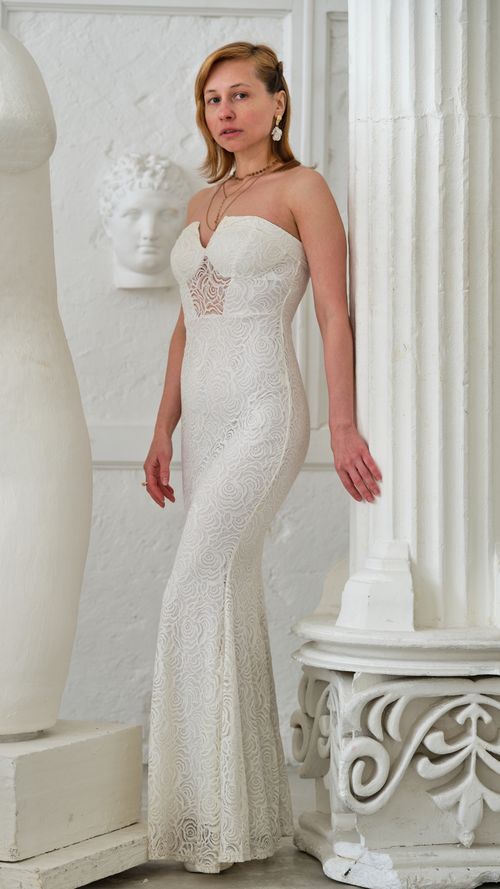 Free Full body of female in white long gown looking at camera near huge column Stock Photo