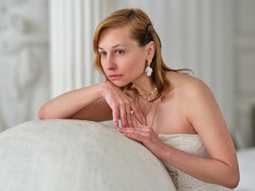 Dreamy alluring woman in white dress pondering