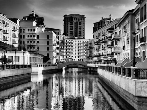 Grayscale Photo of a River Between Buildings