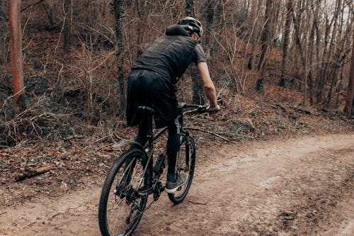 A Man in Black Clothes and Helmet Riding a Mountain Bike