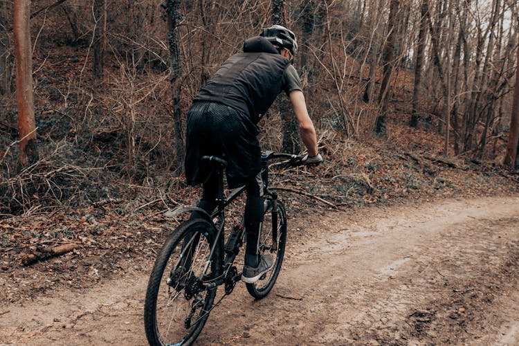 A Man In Black Clothes And Helmet Riding A Mountain Bike