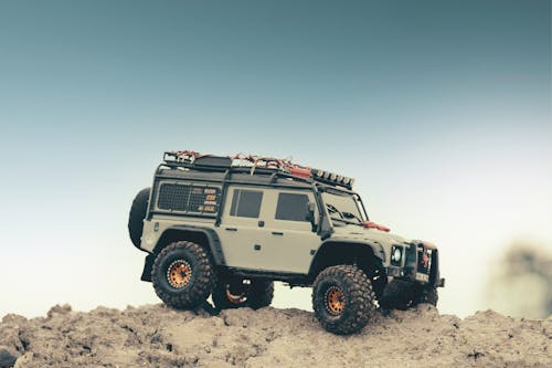 Modern off roader car parked on rough rocky terrain under blue sky in nature