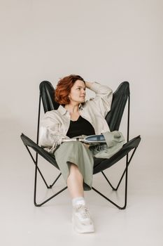 A woman with a prosthetic leg sits comfortably in a chair, embodying casual style and body positivity.