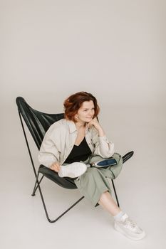 Woman with prosthetic leg sitting comfortably, embracing confidence in casual attire. Studio shot.