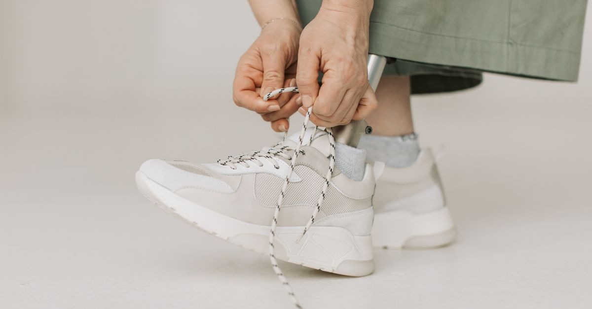 Person with prosthetic leg tying sneakers, promoting body positivity and adaptability.