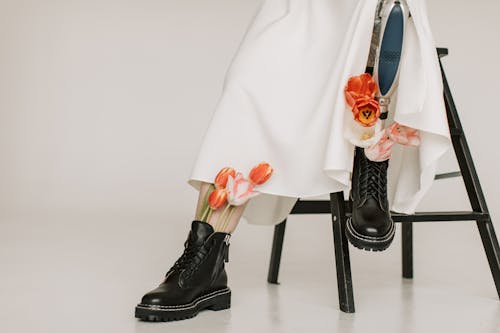 A Woman Wearing Black Boots With Fresh Flowers