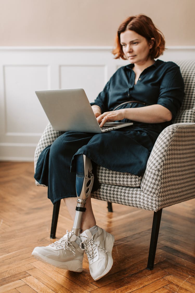 A Woman With Prosthetic Leg Using A Laptop