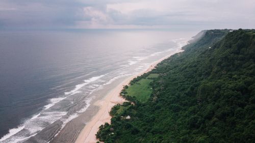 Free Captivating aerial view of ocean waves and lush green cliffs along the coastline. Stock Photo