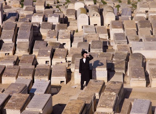 Free A Man in Black Suit Standing Near the Gravestones Stock Photo