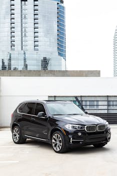 Elegant black SUV parked in cityscape background, showcasing modern architecture.