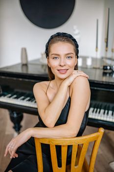 Elegant woman in black dress posing indoors with a grand piano background.