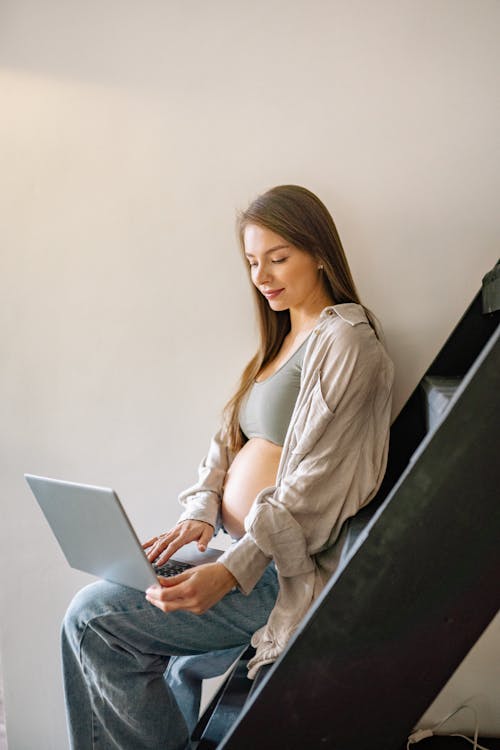 Free Pregnant Woman using Laptop while sitting on a Staircase Stock Photo