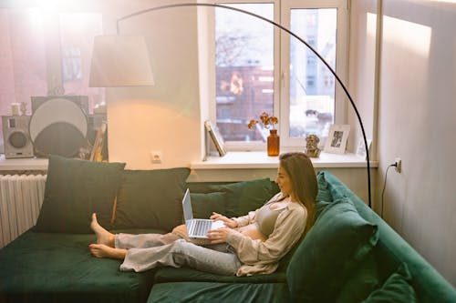 Pregnant Woman using Laptop while sitting on a Sofa