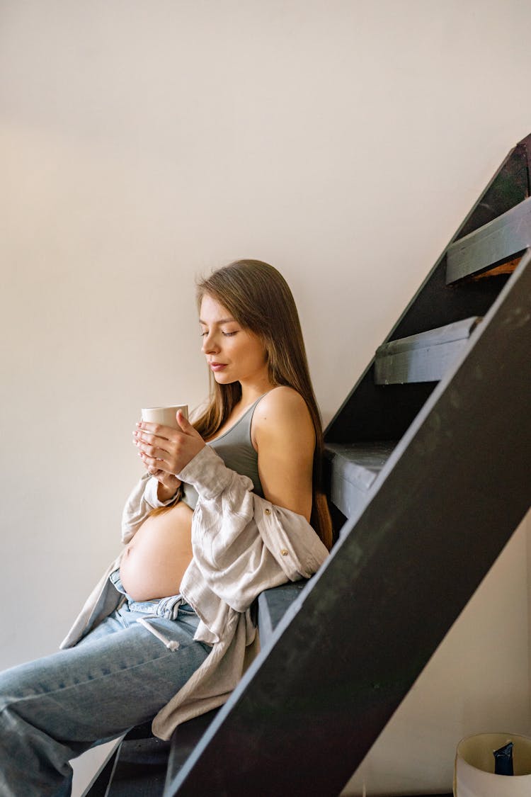 A Pregnant Woman Is Sitting On The Stairs