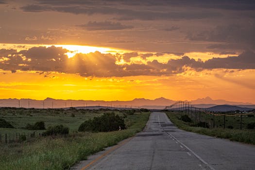 Captivating sunset view over a tranquil road in rural South Africa, showcasing vibrant hues and open landscapes.