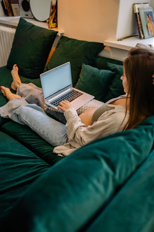 A Pregnant Woman Sitting on  the Sofa Using a Laptop
