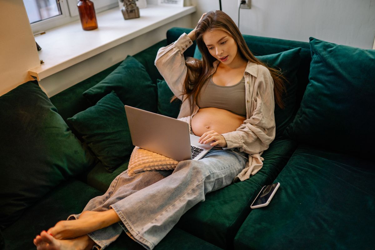 Pregnant woman using a laptop comfortably at home