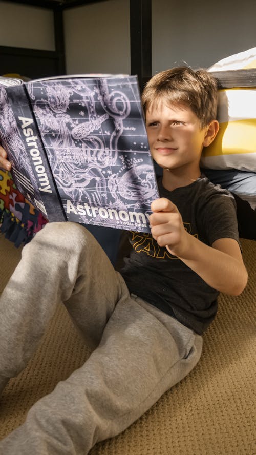 Free A Boy Reading a Book About Astronomy Stock Photo