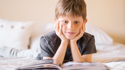 Free Selective Focus Photo of an Amazed Boy Reading a Book Stock Photo