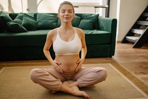 Free Expectant mother practicing meditation at home for healthy living. Stock Photo