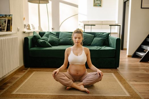 A serene pregnant woman practicing meditation indoors for healthy living.