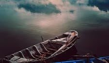 平静的湖面上，一艘古老的木船静静漂浮，倒映着天空