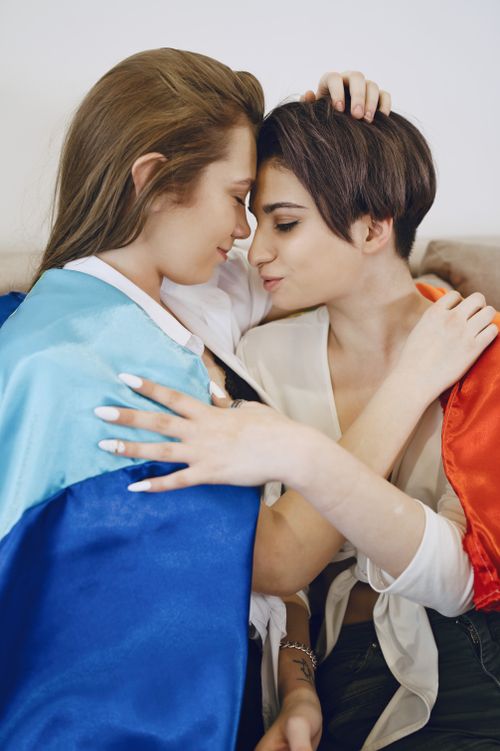 Free A loving embrace between a lesbian couple wrapped in a pride flag, showcasing their intimacy and affection. Stock Photo